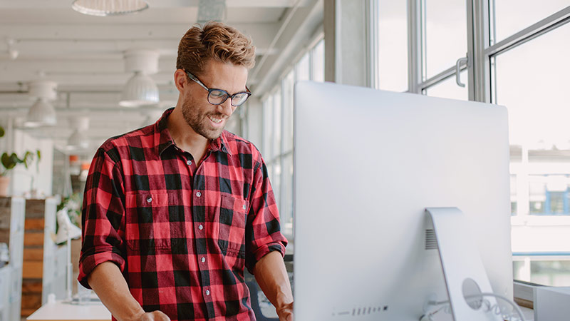 Man smiling in front of his computer monitor