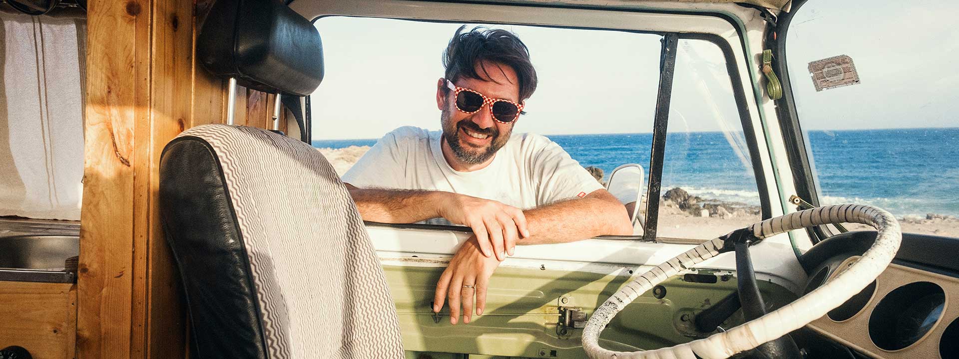 A man looks into his motorhome on the background of the ocean