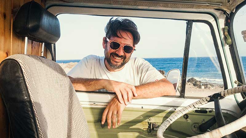 A man looks into his motorhome on the background of the ocean