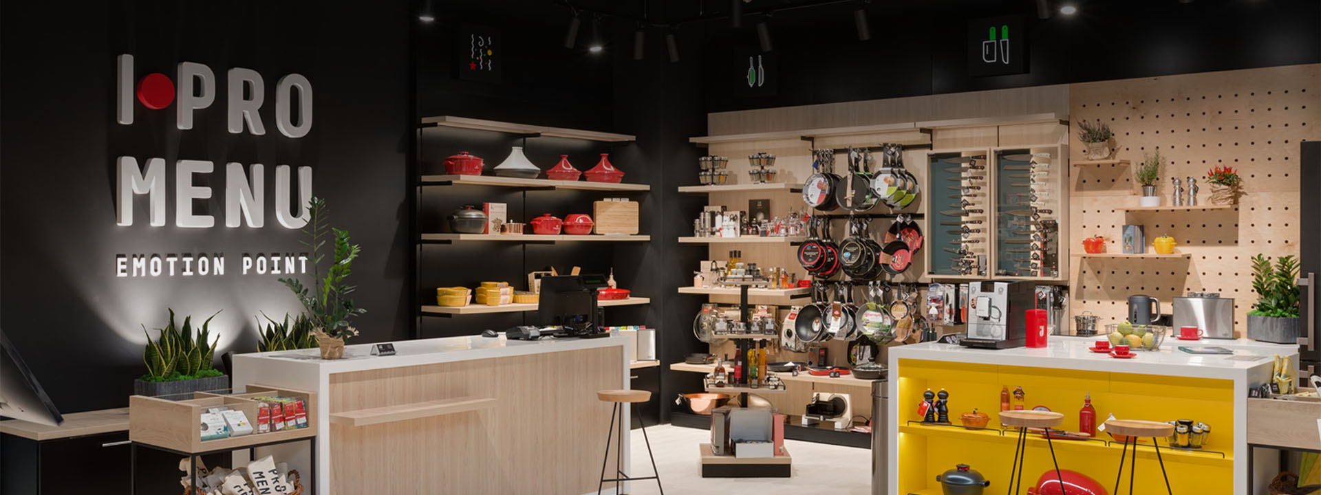 Modern kitchenware store with wooden displays, cookware on shelves, and a sign.