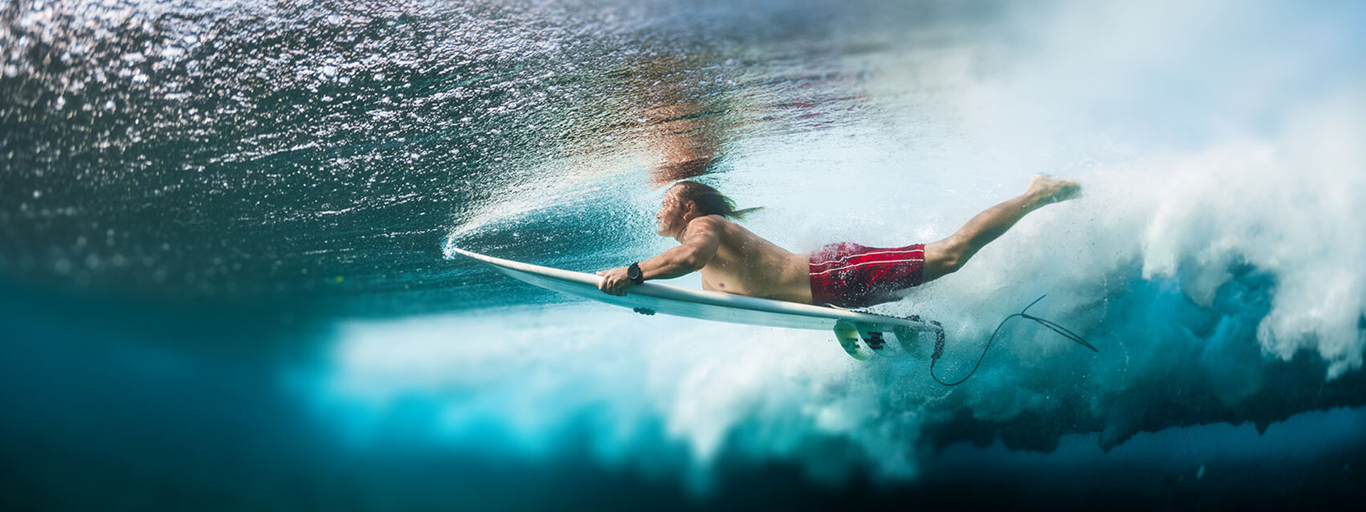 Surfer diving thorugh a wave