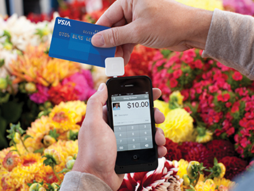 Making payment with Visa card in flower market using Square on mobile phone.